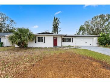 Charming single story home with a well-manicured lawn, beautiful landscaping and a vibrant red front door at 3016 Taunton W Dr, Bradenton, FL 34205