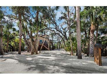 Charming raised beach house with a driveway shaded by mature palms and live oaks at 3376 S Seclusion Dr, Sarasota, FL 34239