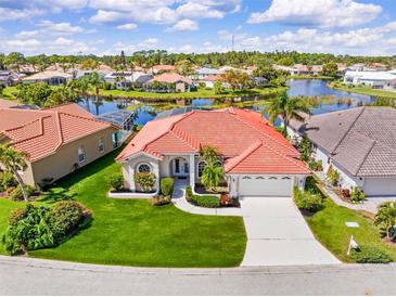 Beautiful waterfront home with lush landscaping, a tile roof, and a lovely circular window on a sunny day at 4173 Hearthstone Dr, Sarasota, FL 34238
