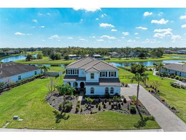 Stunning aerial view of a two-story home with tile roof, landscaped yard, and serene lake views at 4789 Vasca Dr, Sarasota, FL 34240