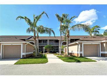 Inviting condo exterior featuring palm trees, attached garages, and well-maintained landscaping at 5250 Hyland Hills Ave # 1514, Sarasota, FL 34241