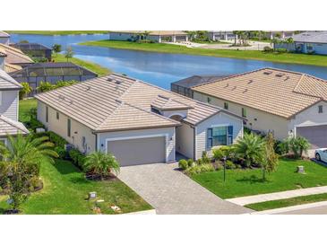 Beautiful single-story home with a paver driveway and tile roof near a serene lake at 5317 Coral Reef Way, Bradenton, FL 34211