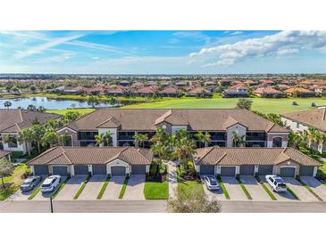 Stunning aerial view of the condos with lush landscaping, a lake, and golf course at 5517 Palmer Cir # 203, Bradenton, FL 34211