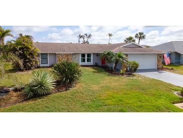 Charming single-story home features a well-manicured lawn and tropical landscaping at 5859 Lincoln Rd, Venice, FL 34293