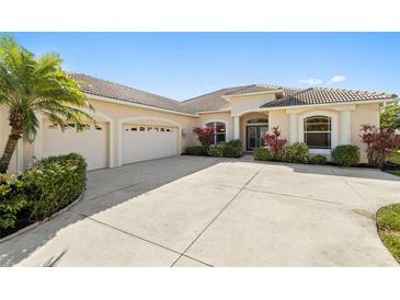 Elegant home featuring a barrel tile roof, a spacious driveway, and a lush tropical landscaping in the front yard at 12736 Penguin Dr, Bradenton, FL 34212