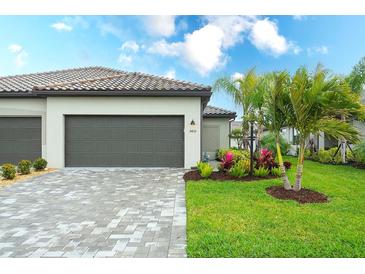 Lovely home exterior with a brick driveway, well-maintained lawn, and beautiful landscaping at 5433 Mystic Water Cv, Lakewood Ranch, FL 34211