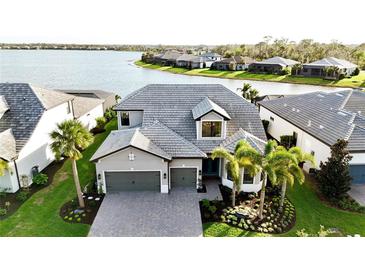 Stunning two-story home features a stone driveway, two-car garage, beautiful landscaping, and gorgeous water view at 7717 Mainsail Ln, Sarasota, FL 34240