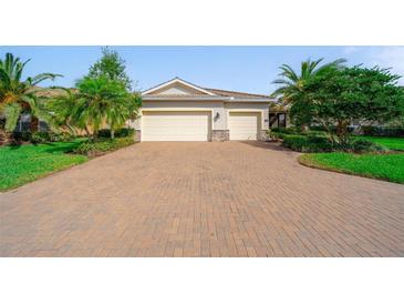 Exterior view of home showing three-car garage, beautiful landscaping, and brick-paved driveway at 8007 River Preserve Dr, Bradenton, FL 34212