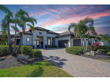 Beautiful Mediterranean-style home with a brick driveway, two-car garage, and palm tree landscaping at 11511 Harbourside Ln, Parrish, FL 34219