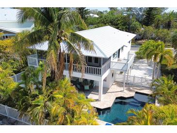 Aerial view showcasing the home with a private pool, screened porch, and lush landscaping in a desirable location at 123 Hammock Rd, Anna Maria, FL 34216