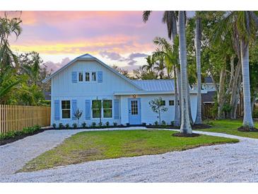Charming two-story home with a gravel driveway, light blue shutters, and lush tropical landscaping at 206 23Rd W St, Bradenton, FL 34205