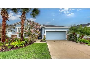 Charming single-story home with a well-manicured lawn, featuring a two-car garage and colorful landscaping at 5068 Inshore Landing Dr, Apollo Beach, FL 33572