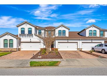 Charming townhome featuring a two-car garage, brick-paved driveway, and well-maintained landscaping at 11831 Brookside Dr, Bradenton, FL 34211