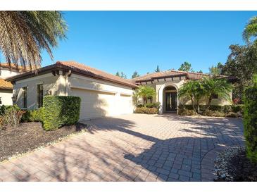 Charming home showcasing a brick driveway, a two-car garage, and tropical landscaping at 15403 Leven Links Pl, Lakewood Ranch, FL 34202