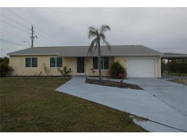 Charming one-story home with a well-maintained lawn, a palm tree and an attached garage at 1717 Alton Rd, Port Charlotte, FL 33952
