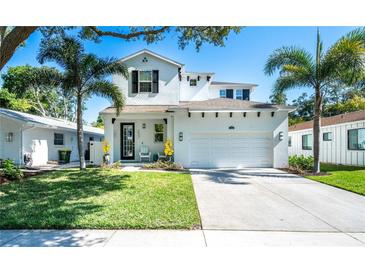 Charming two-story home featuring a well-manicured lawn, a two-car garage, and decorative palm trees at 2283 Arlington St, Sarasota, FL 34239
