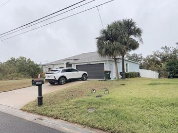 Charming single-story home featuring a well-maintained lawn, two palm trees, and a driveway with a parked car at 3650 S Sumter Blvd, North Port, FL 34287