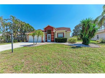 Lovely home with lush green lawn, landscaped with palm trees and brick-lined garden beds at 5103 73Rd E St, Bradenton, FL 34203