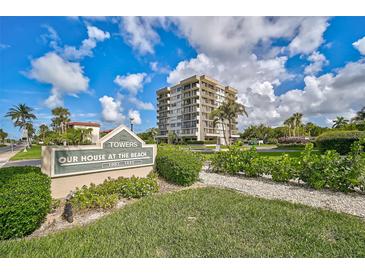 Beautiful condominium building, Our House at the Beach, featuring lush landscaping and blue skies in a tropical location at 1001 Beach Rd # A203, Sarasota, FL 34242