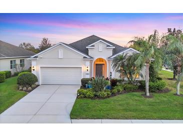 Charming single-story home with a well-manicured lawn, lush landscaping, and an attached two-car garage at 4623 Claremont Park Dr, Lakewood Ranch, FL 34211