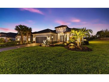 Elegant home exterior at twilight, featuring lush landscaping, palm trees, and a well-lit entrance at 4735 Trento Pl, Bradenton, FL 34211