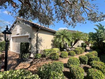 Beautiful home exterior with lush landscaping, manicured hedges, and a charming brick walkway leading to the entrance at 5031 Serata Dr, Bradenton, FL 34211