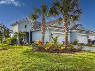 Beautiful light-blue two-story home with lush landscaping and a three-car garage at 6280 Cassia St, Bradenton, FL 34203