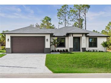 Charming single-story home featuring a well-maintained lawn, modern architectural details, and a two-car garage at 2375 Saybrook Ave, North Port, FL 34286