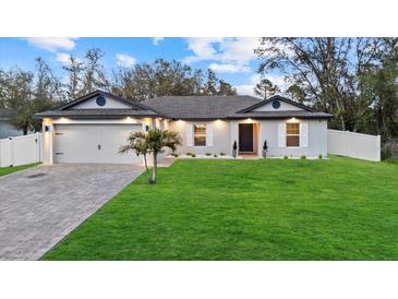 Charming single-story home with a well-manicured lawn, white shutters, a paver driveway, and a two car garage at 3266 Lanai Ave, North Port, FL 34288