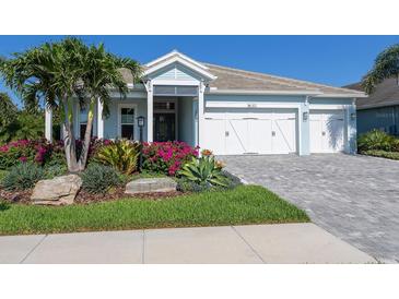 Charming single-Gathering home featuring a three-car garage and beautifully landscaped front yard with flowering plants at 813 Tailwind Pl, Sarasota, FL 34240