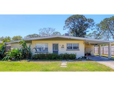 Charming single-story home with a well-maintained lawn and a covered carport on a sunny day at 2564 Wood St, Sarasota, FL 34237