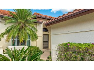 Charming home featuring lush landscaping, a tile roof, and a welcoming front entrance with a decorative window above the door at 4909 Clubview E Ct, Bradenton, FL 34203