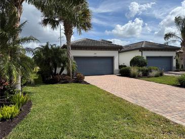 Charming villa with a brick driveway, two-car garage, and lush tropical landscaping at 12245 Marsh Pointe Rd, Sarasota, FL 34238