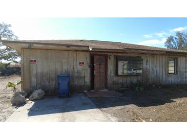 Exterior view of a one-story home featuring a rustic wooden facade, and a partially opened front door at 1316 56Th Avenue E Ter, Bradenton, FL 34203