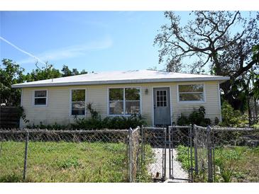 Inviting single-story home featuring a fenced yard and a well-lit entryway beneath a light blue sky at 1715 17Th W Ave, Bradenton, FL 34205