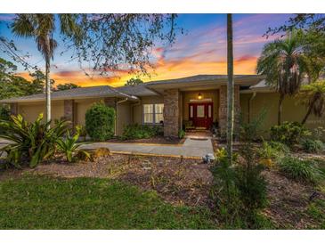 Charming home featuring a landscaped front yard, brick accents, and a welcoming red front door at sunset at 201 Eaglenook Way, Osprey, FL 34229