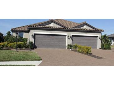 Charming one-story home featuring a tile roof, gray exterior, brick driveway, and a spacious two-car garage at 4762 Tortona Ct, Lakewood Ranch, FL 34211