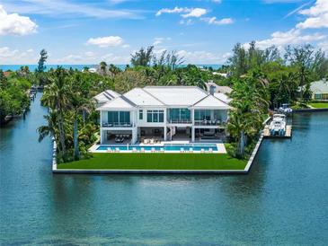 Stunning waterfront home with a modern design, lush landscaping, and a beautiful pool overlooking the water at 612 Juan Anasco Dr, Longboat Key, FL 34228