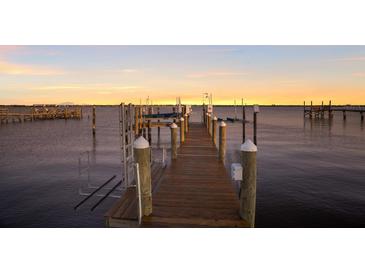 Waterfront dock with a boat lift featuring sunset views and ample space for relaxing and entertaining at 766 Bayshore Dr, Terra Ceia, FL 34250