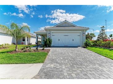 Charming single-story home with a paved driveway, lush landscaping, and a two-car garage under a blue sky at 995 Waterline Ct, Sarasota, FL 34240