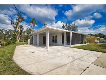Single-story home featuring a covered parking area, a screened porch, and mature landscaping at 221 Laurel E Rd, Nokomis, FL 34275