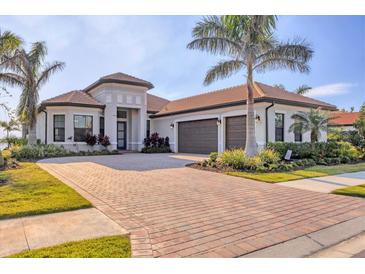 Beautiful single-story home showcasing a brick driveway, lush landscaping, and an attached two-car garage at 525 Maraviya Blvd, Nokomis, FL 34275