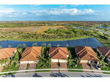 Stunning aerial view of single-Gathering homes with tile roofs, set against a serene lake and lush green landscape at 24068 Canterwood Way, Venice, FL 34293