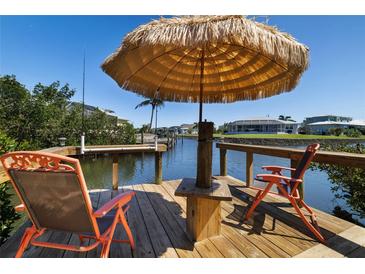 Relaxing waterfront dock featuring a tiki umbrella, chairs, and beautiful canal views at 2502 Larkspur Dr, Punta Gorda, FL 33950