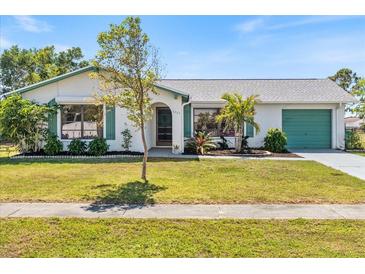 Charming single-story home featuring a well-manicured lawn, attached garage and verdant landscaping at 6335 Granger Rd, Port Charlotte, FL 33981