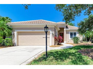 Well-manicured front yard with mature trees, a lamp post, and lush green grass creating a welcoming entrance at 9734 51St Terr E, Bradenton, FL 34211