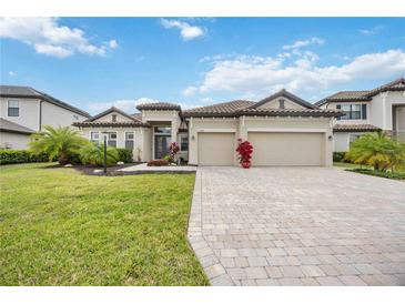 Beautiful single-story home featuring a tile roof, three-car garage, paver driveway and lush landscaping at 17519 Polo Trl, Lakewood Ranch, FL 34211