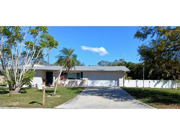 Charming single-story home with a well-manicured lawn, mature trees, and a paved driveway at 3013 Yarmouth W Dr, Bradenton, FL 34205