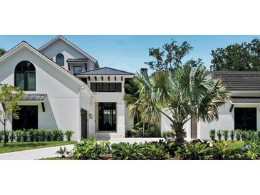 Elegant two-story home with manicured landscaping, a dark roof, and modern architecture at 329 Bird Key Dr, Sarasota, FL 34236