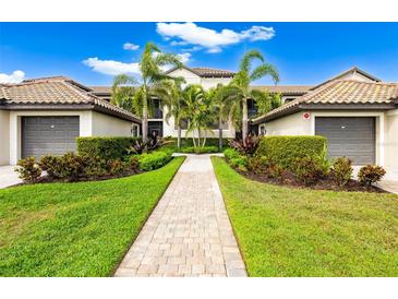 Beautifully landscaped condo building with manicured lawn, palm trees and paver walkway leading to the entrance at 5694 Palmer Cir # 204, Lakewood Ranch, FL 34211